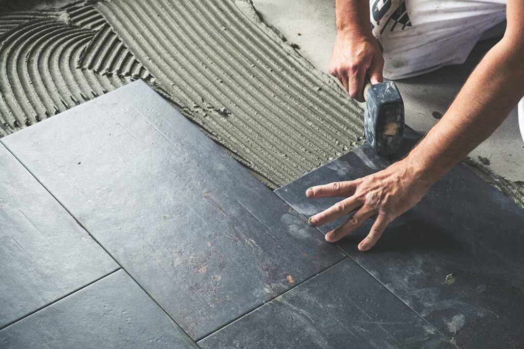 A family removing muddy shoes on a tiled entryway floor inside a bright, lived-in home.