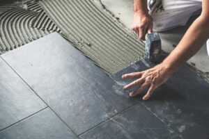 A family removing muddy shoes on a tiled entryway floor inside a bright, lived-in home.
