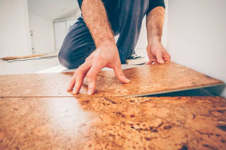 A kitchen floor showing luxury vinyl tile beside ceramic tile samples on a work surface.